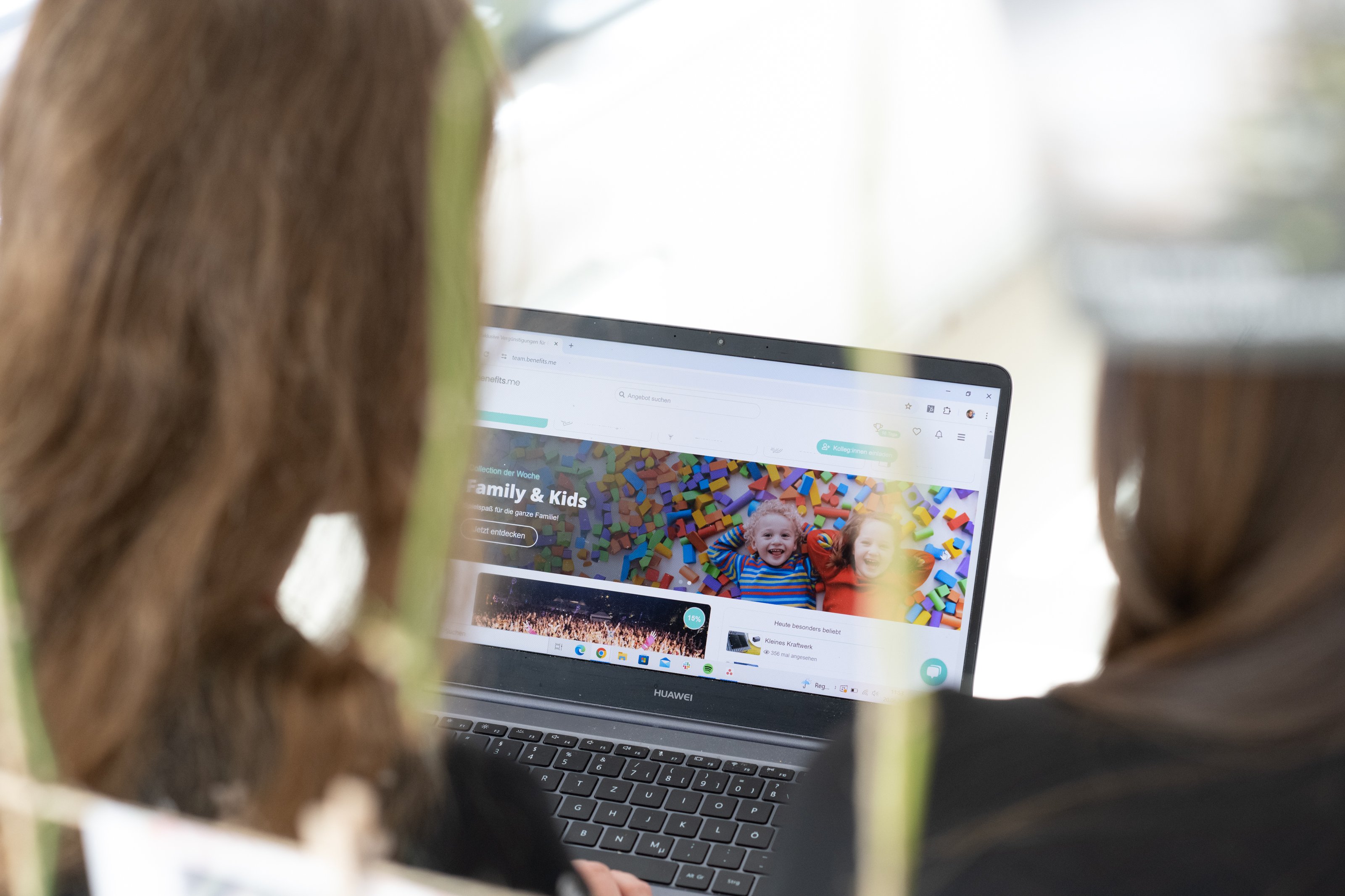 Blick über die Schulter einer Mitarbeiterin auf das Portal von benefits.me mit Rabattangeboten auf dem Laptop-Bildschirm